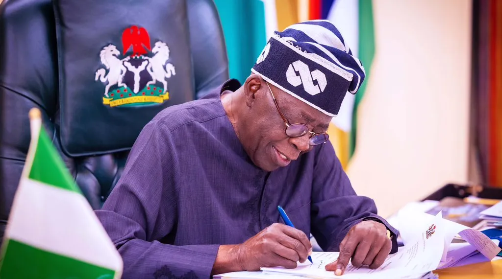 President Bola Ahmed Tinubu signing documents.webp